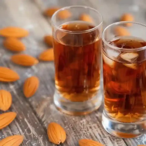 2 Copa de amaretto casero servida con hielo y decoración de naranja en ambiente de coctelería
