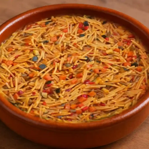 Plato de fideos con verduras españoles servidos en cazuela tradicional con pimientos, calabacín y zanahoria